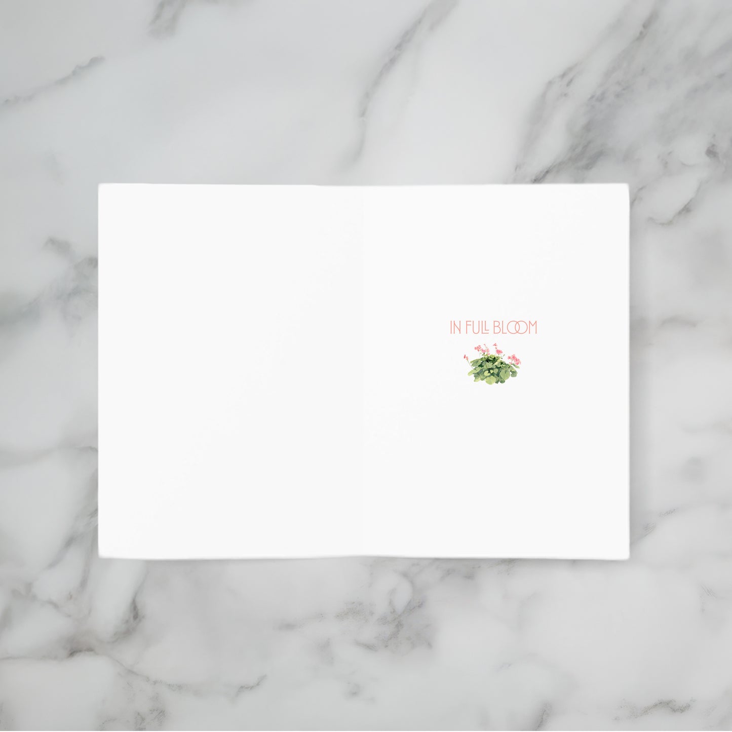 White card with floral design and text 'In Full Bloom' on a marble background