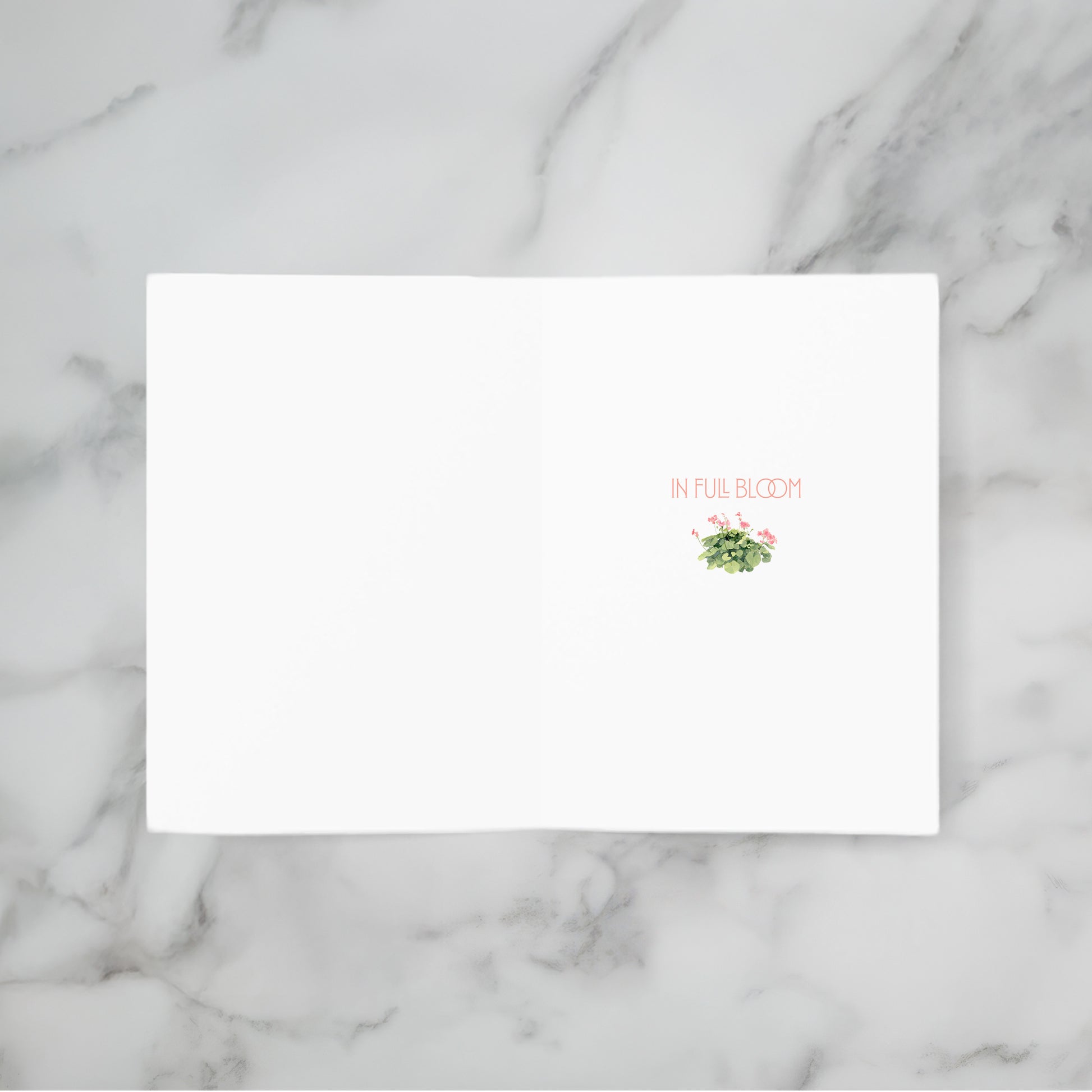 White card with floral design and text 'In Full Bloom' on a marble background