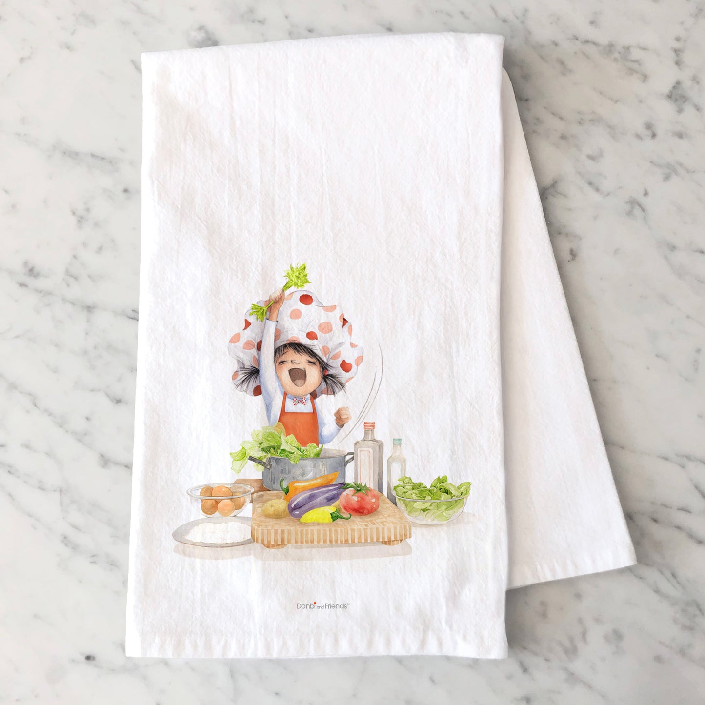 White towel with a colorful illustration of a child in a kitchen on a marble surface