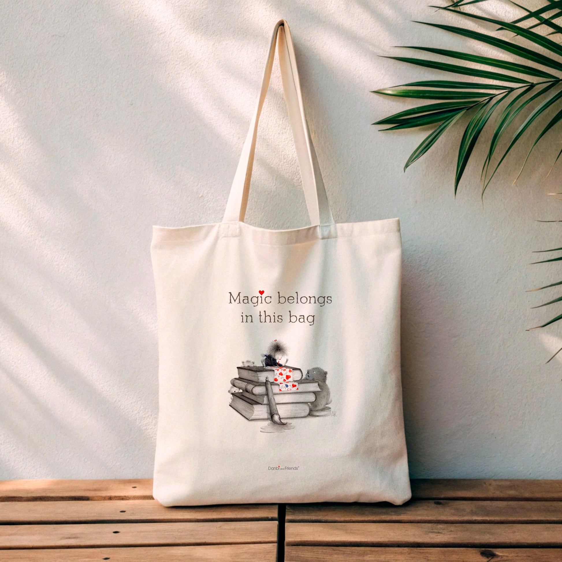 Tote Bag with Books and creatures drawing hearts with text that says Magic Belongs in this Bag