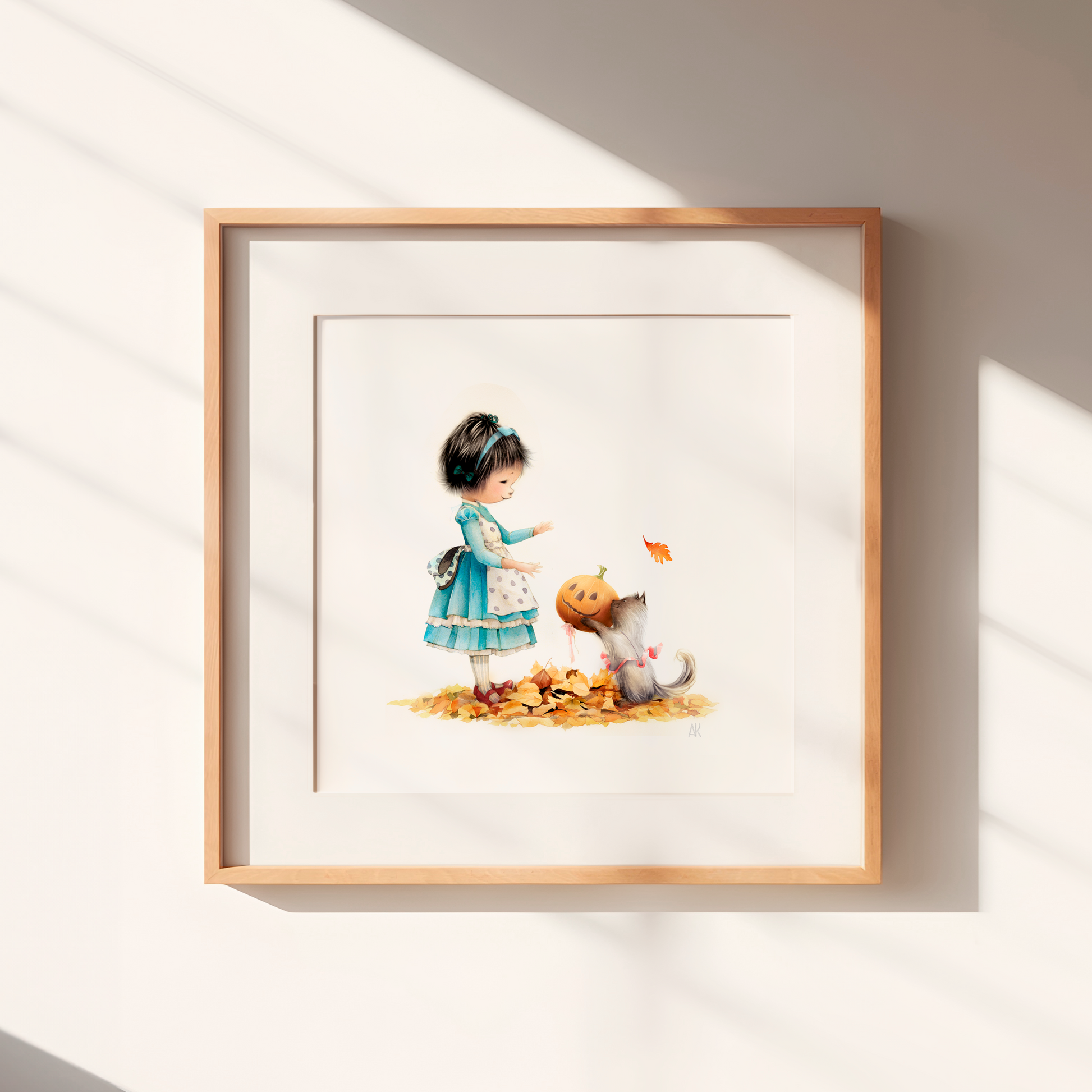 Framed artwork of a girl with a cat and pumpkin on a white wall