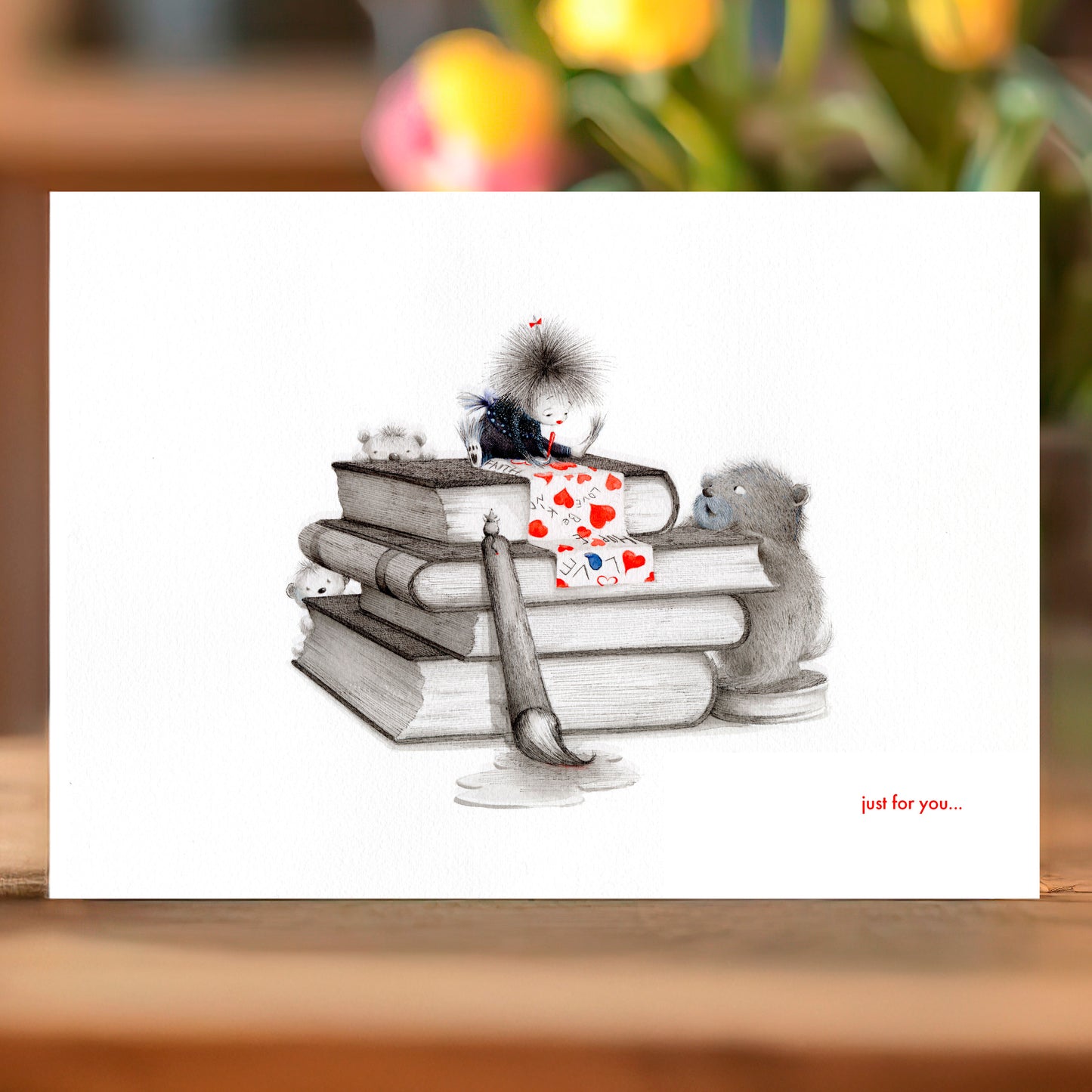 Illustration of a cat with a book and hearts on a card with 'just for you...' text.